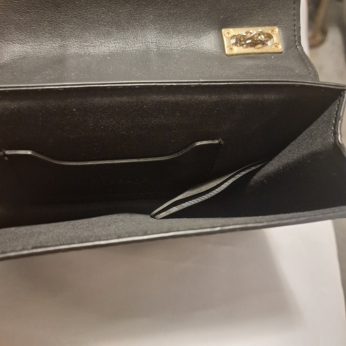 Close view inside the bag showing its dark lining and narrow open interior pocket.