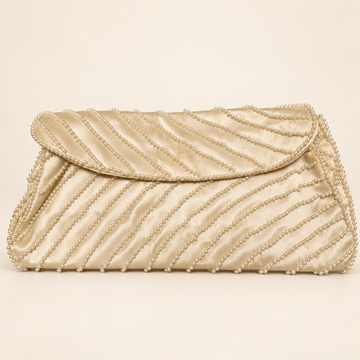 Cream satin-like evening clutch with diagonal faux-pearl rows, shown closed from the front