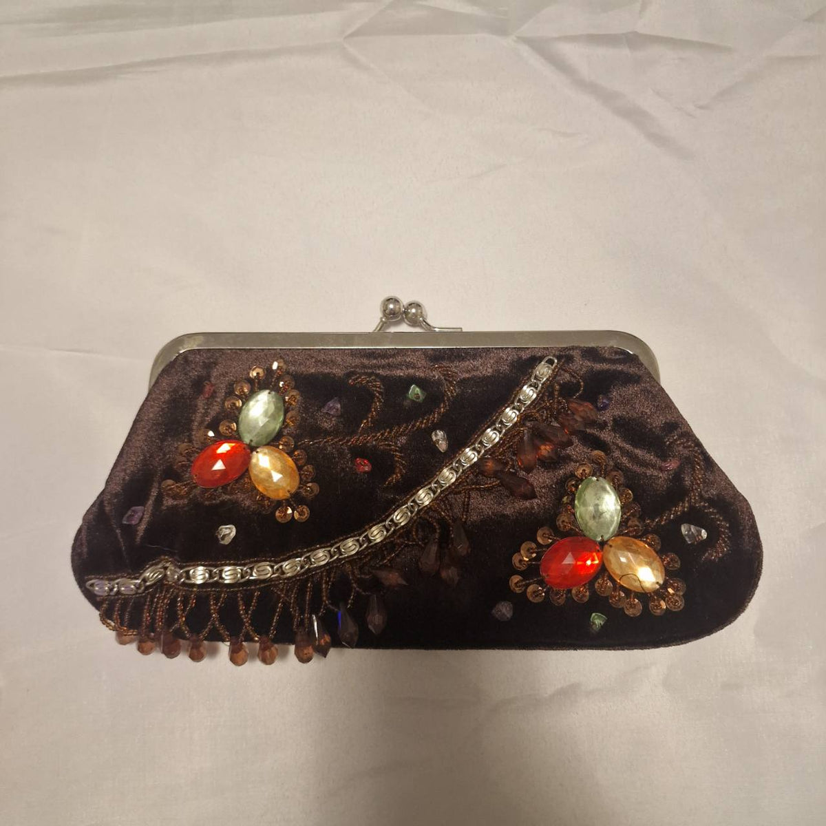 Front of unbranded brown velvet evening bag with jewel-coloured stones, sequins, beadwork and silver-tone frame