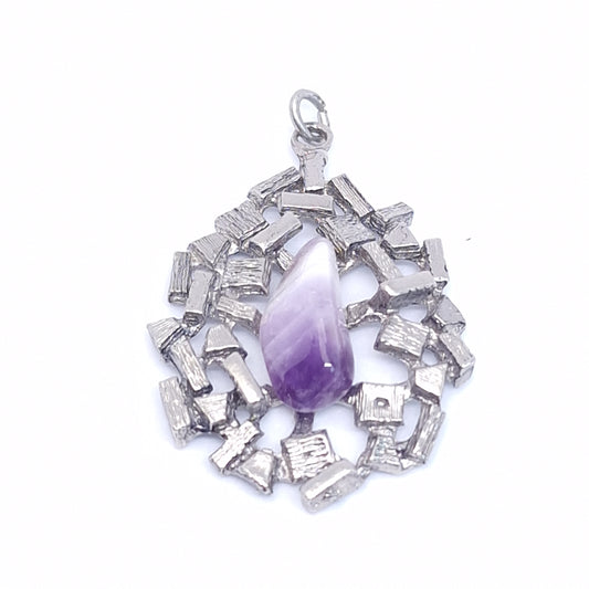 Close angled view of a brutalist silver-tone pendant with a polished teardrop amethyst-coloured stone and textured metal blocks
