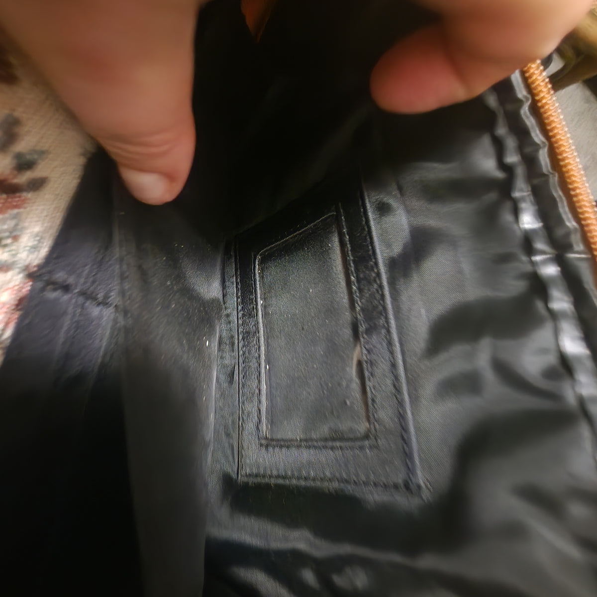 Close-up of a black slip pocket inside the bag lining held open by a thumb