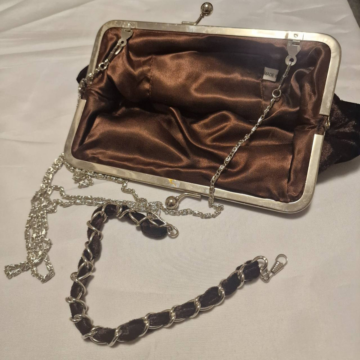 Open evening bag showing brown satin lining, metal frame, detachable silver-tone chain and short handle