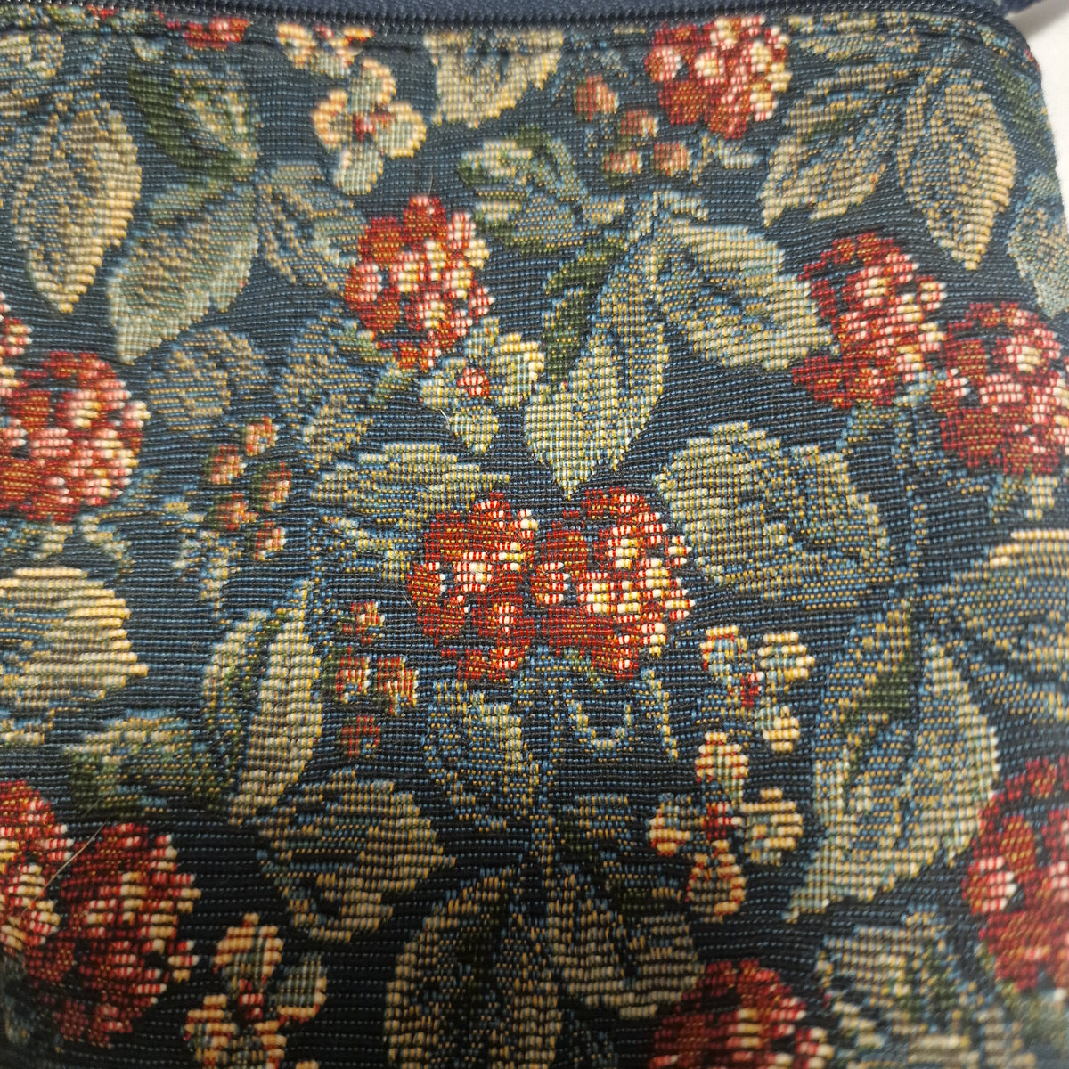 Close-up of the woven berry and leaf tapestry fabric on the bag