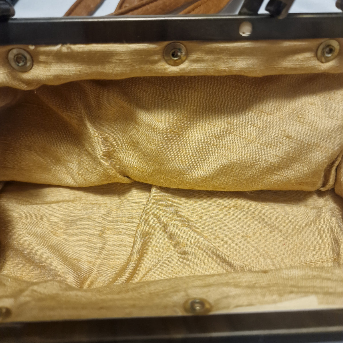 Inside of the bag showing gold slubbed lining attached to the metal frame with round rivets