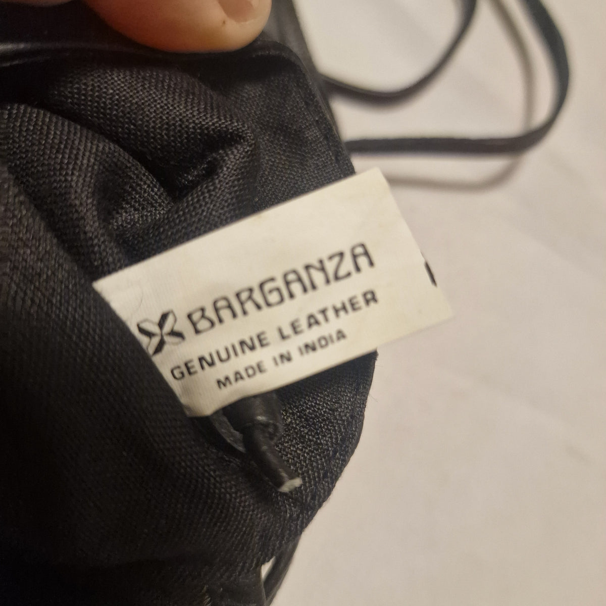 Close-up of the white interior label reading Barganza Genuine Leather Made in India on black lining