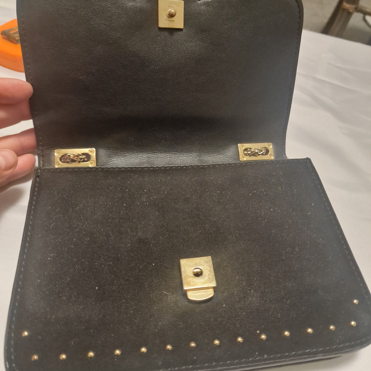 Open bag showing the inner flap, gold-tone closure hardware and black interior.