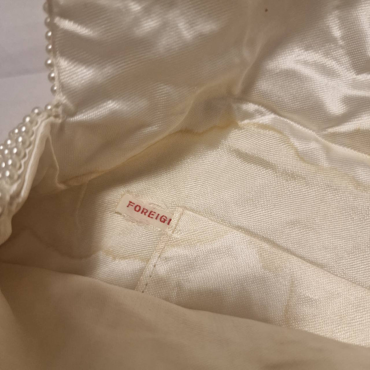 Interior label on the cream clutch, partially readable as FOREIGN