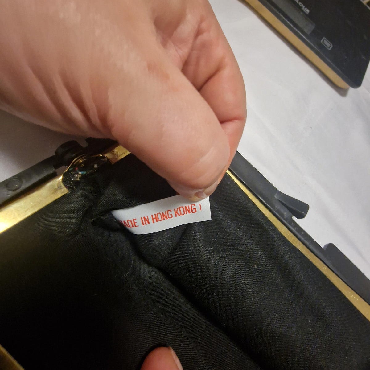 Hand holding a white Made in Hong Kong label inside a black fabric-lined frame bag