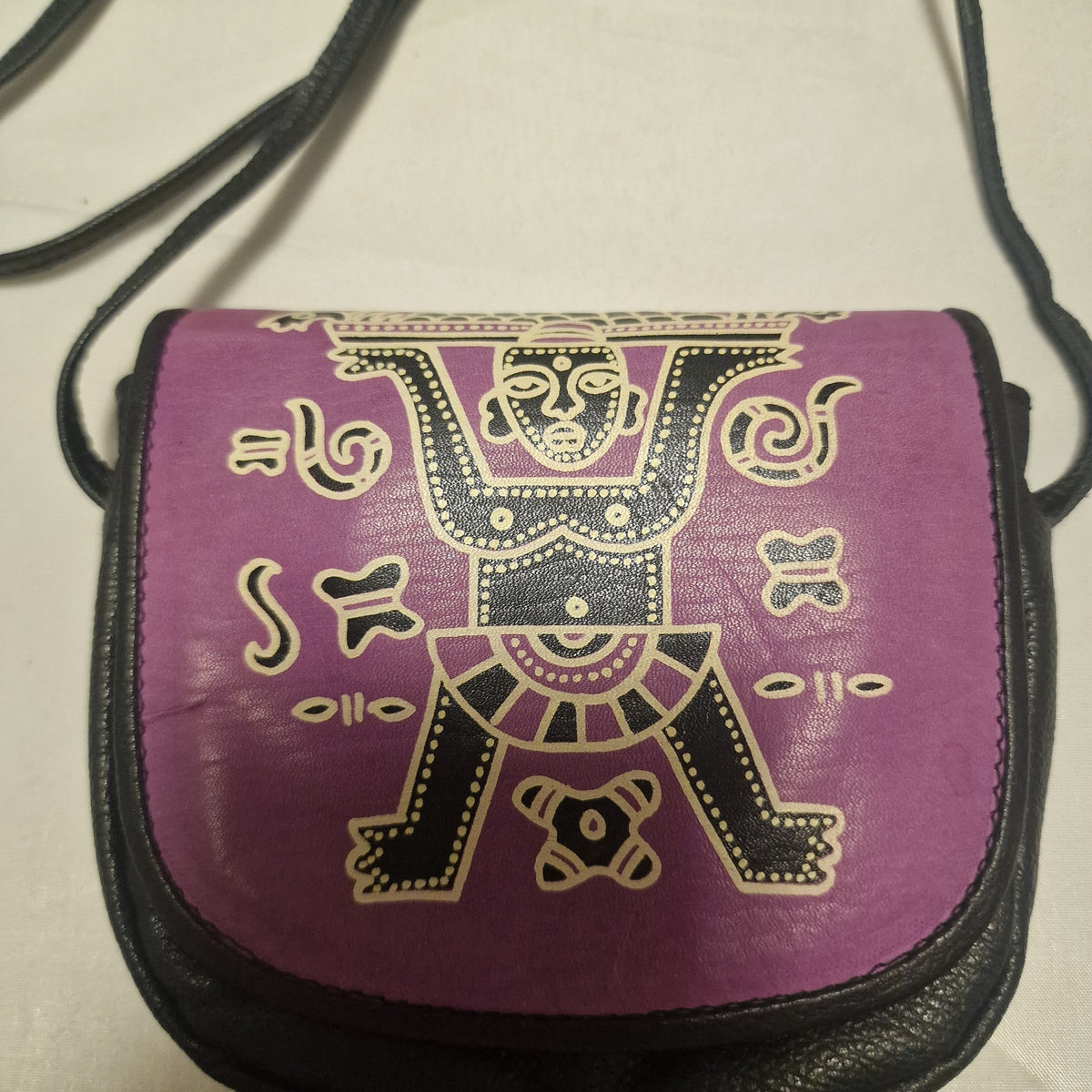 Close-up of the purple leather flap printed with a black and cream tribal-style figure and symbols