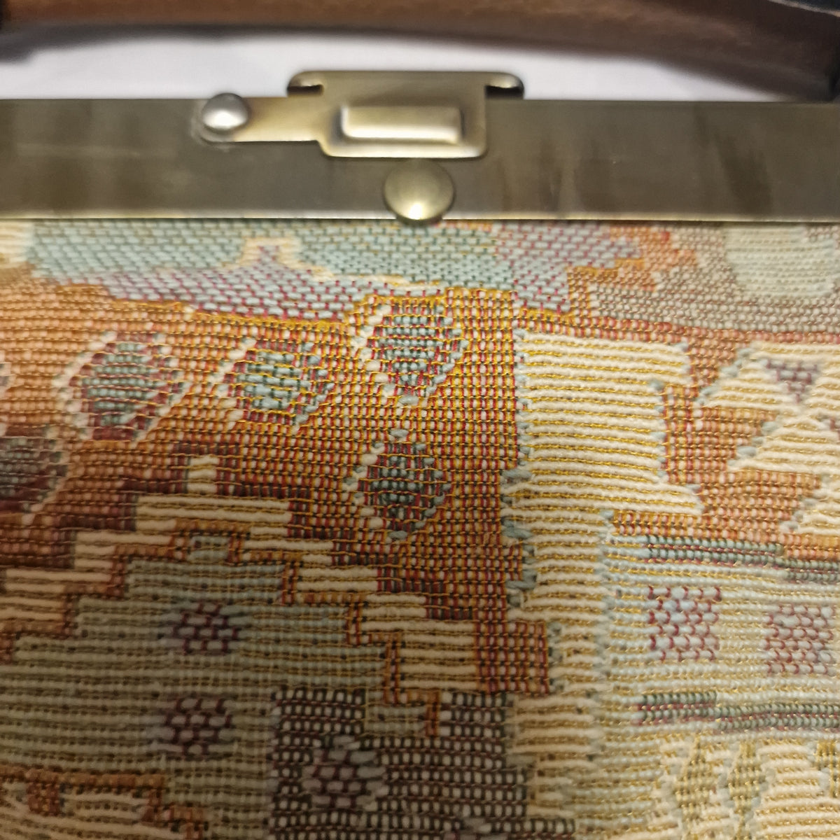 Close view of woven kilim-style tapestry fabric beside the brass clasp plate