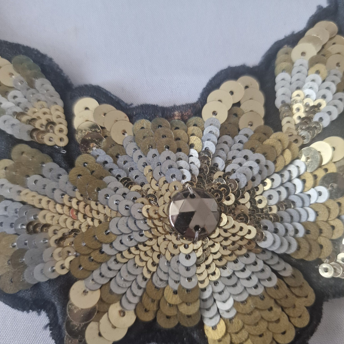 Close-up of gold and silver sequin floral detail with faceted centre on statement necklace