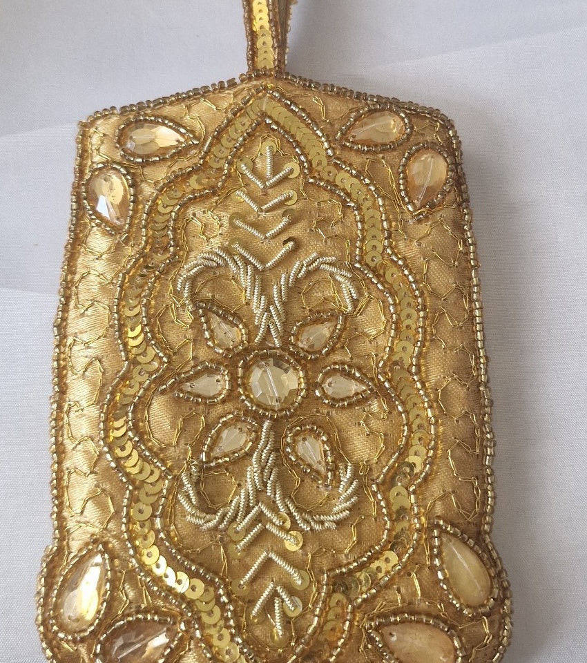 Close-up of ornate gold bead embroidery, sequins and faceted amber-tone stones
