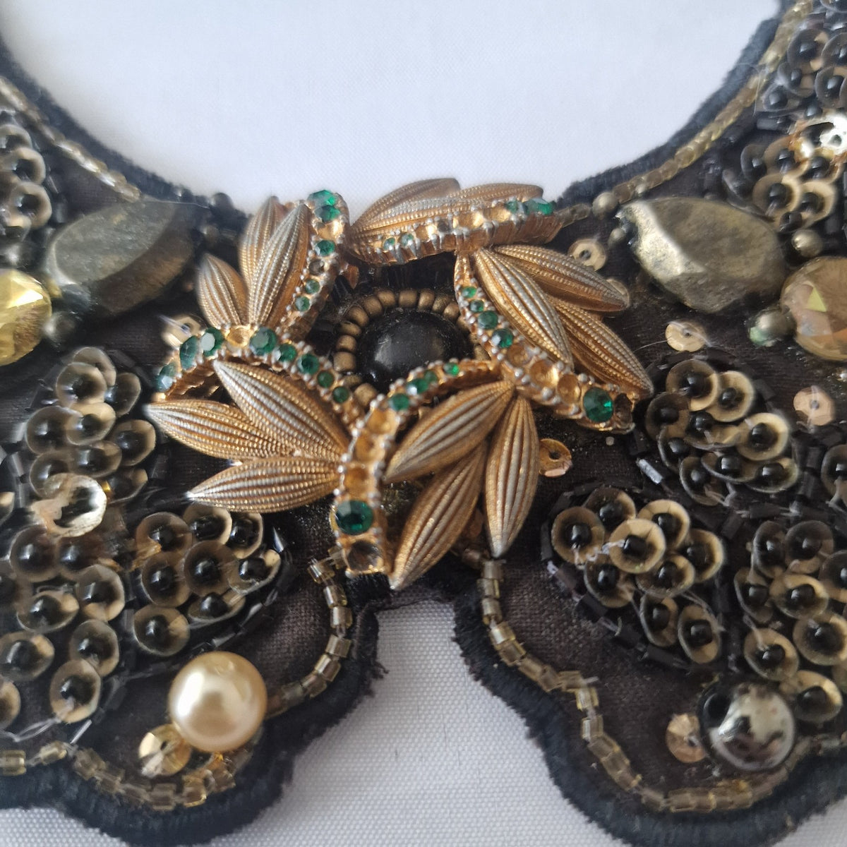 Close-up of gold-tone floral centre with green accents on vintage bib necklace